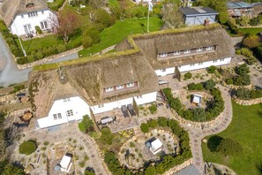 A large estate with multiple buildings, including a main house with a thatched roof, several smaller outbuildings, and a well-maintained garden with stone pathways and various plants. - Gaat 7 Der Junge Heinrich - Gaat 7 - Wohnen im Historischen Ortskern Keitum (Sylt)