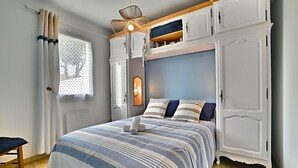 A bedroom with a bed, a nightstand, a wardrobe, and a window with curtains. - Les Pâquerettes by Interhome (Ile d'Oléron)