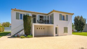 A two-story house with a balcony, a garage, and a paved driveway.