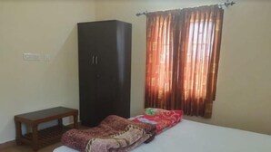 A bedroom with a bed, a wardrobe, a bench, and a window with curtains.