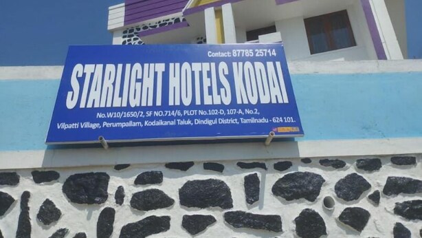 A signboard for Starlight Hotels Kodai with contact details and address.