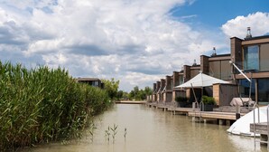 Ein Flussufer-Hotel mit moderner Architektur, Sitzgelegenheiten im Freien und einem Steg.