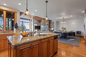 Eine geräumige Küche mit Granit Arbeitsplatten, Holzschränken und einer großen Kochinsel.