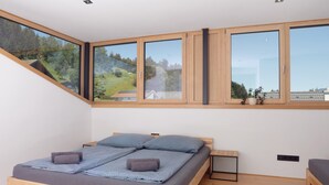 Een moderne slaapkamer met dakraam, een bed met blauw beddengoed en een klein nachtkastje.