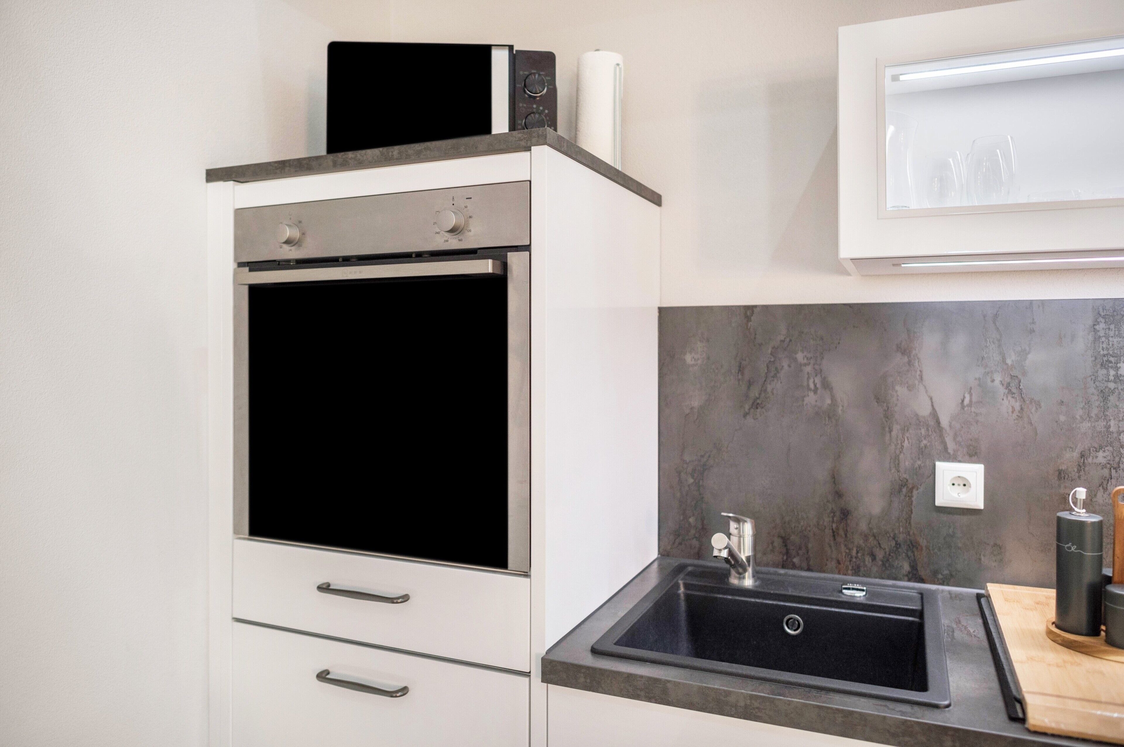A kitchen with a built-in oven, a sink, and a countertop.