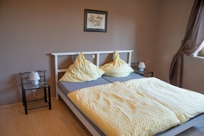 A bed with a white headboard, two pillows, a white lamp on a bedside table, and a framed picture on the wall. - Apartment 'Ferienwohnung Maintalblick' with Private Terrace, Private Garden and Wi-Fi (Eltmann)