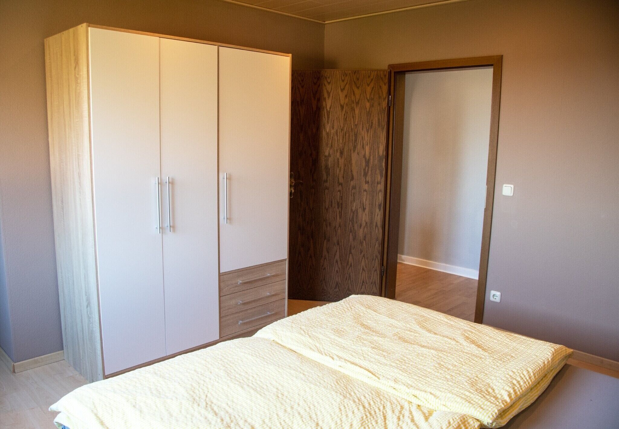 A bedroom with a bed, wardrobe, and a mirror.