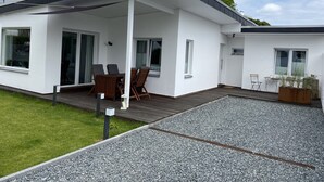Una casa moderna con un porche cubierto, comedor y un pequeño jardín.