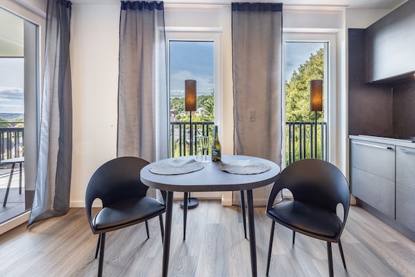 A modern room with a round table, two chairs, a bottle, and a wine glass.