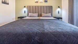 Ein Bett mit gesteppter Bettdecke, zwei Nachttische mit Lampen und drei Bilder an der Wand.