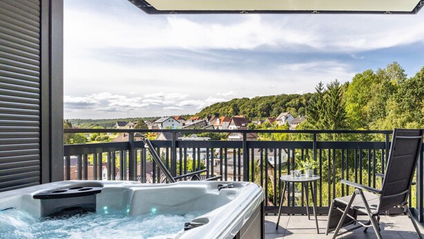 Ein Whirlpool auf einem Balkon mit Blick auf Häuser und Bäume.