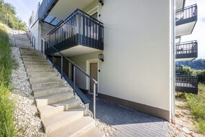 A staircase leading to a building with balconies, a door, and a paved area.