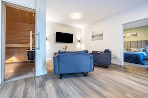 A modern room with a sofa, a TV mounted on the wall, and a bed with a headboard.