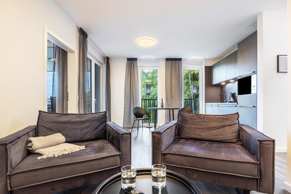 A modern room with two leather sofas, a small table with glasses, and a view to a balcony.
