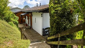 A house with a tiled roof, a wooden porch, and a small garden area.