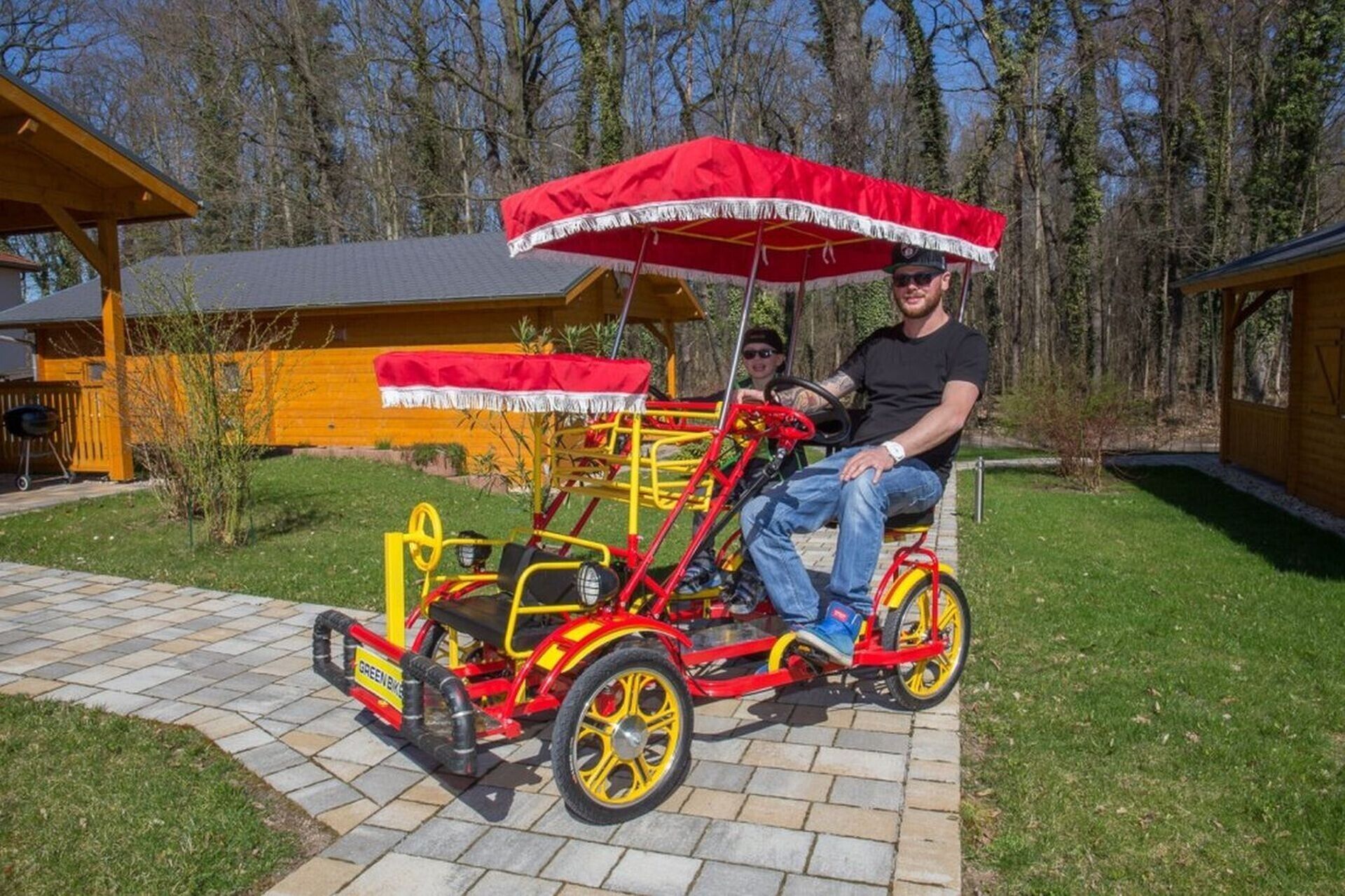 A red and yellow tricycle with a canopy, parked on a paved area.