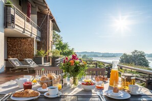 Una mesa de desayuno con diversos alimentos y vistas a un lago.