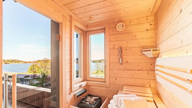 A wooden sauna with a view of a lake, a sauna bench, and a towel rack. - Apartment "Seen-Sucht" with Lake View, Shared Garden & Wi-Fi (Bad Endorf)