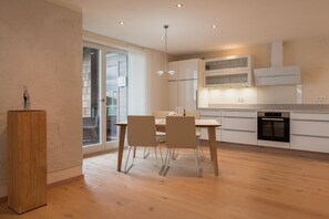 A modern kitchen with wooden flooring, a dining table with chairs, and built-in cabinets.