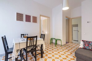 A dining area with a table set for four, two chairs, and a green stool.