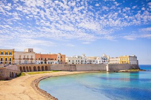 A coastal town with a curved waterfront, historic buildings, and a prominent fortification.
