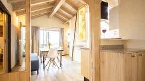 A modern kitchen with wooden cabinets, a dining area with a table and chairs, and a large window providing natural light. - Apartment "Ambiente" with Lake View, Shared Garden & Wi-Fi (Bad Endorf)
