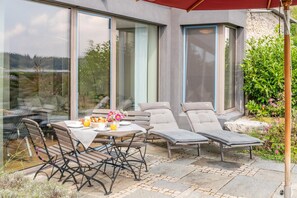 A patio with a table, chairs, and a lounge chair.