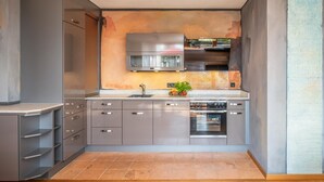 A modern kitchen with grey cabinetry, a stainless steel range hood, and a built-in oven. - Apartment "Wellvital" with Private Terrace & Wi-Fi (Bad Endorf)