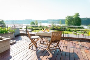 Una terraza de madera con una mesa y sillas con vista a un lago.