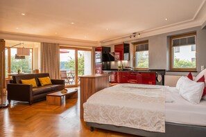 Un dormitorio moderno con una cama grande, un sofá, una mesa de centro y una cocina con armarios rojos.