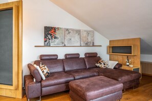 Una sala de estar moderna con un sofá modular, un televisor montado en la pared y una obra de arte abstracta.