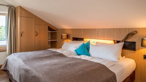 Une chambre à coucher avec un lit, des oreillers, une lampe de chevet, une armoire en bois et une fenêtre.