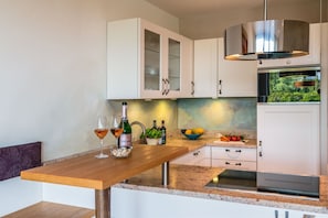 Una cocina moderna con armarios blancos, una mesa de madera y un horno empotrado.