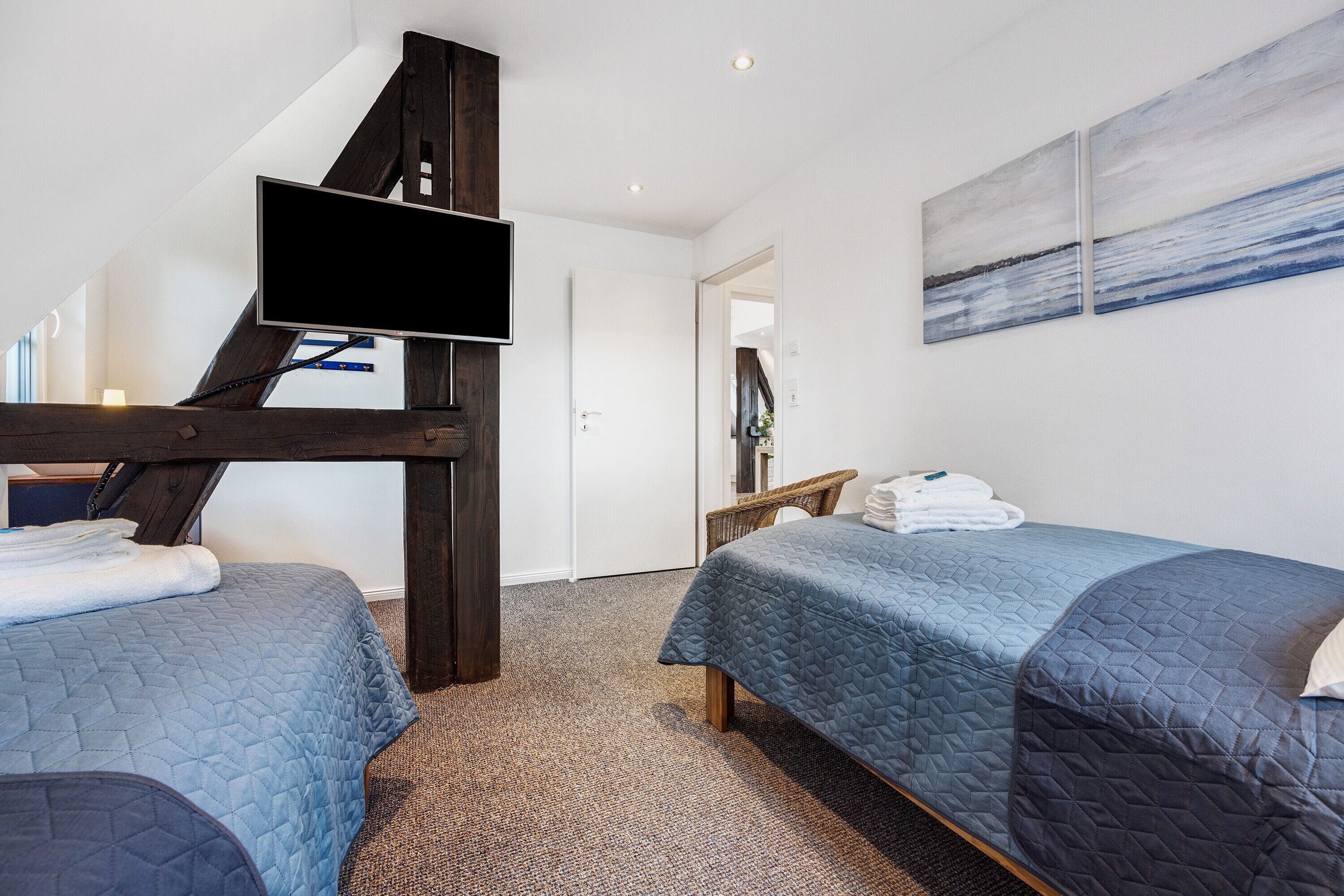 Habitación de hotel con dos camas, un televisor y obras de arte en la pared.