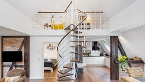 Een modern interieur met een spiltrap, een slaapkamer op een entresol, een keuken en een zithoek.