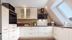 Een moderne keuken met inbouwapparatuur, een dakraam en een houten vloer.