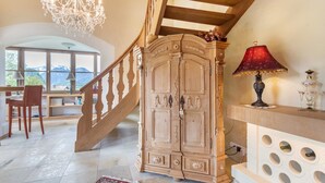 A grand staircase with a wooden finish, a chandelier, and a large wooden cabinet with intricate carvings. - Spacious Group Holiday Home in Chiemgau – Ideal for Families & Friends (up to 10 guests) (Unterwössen)