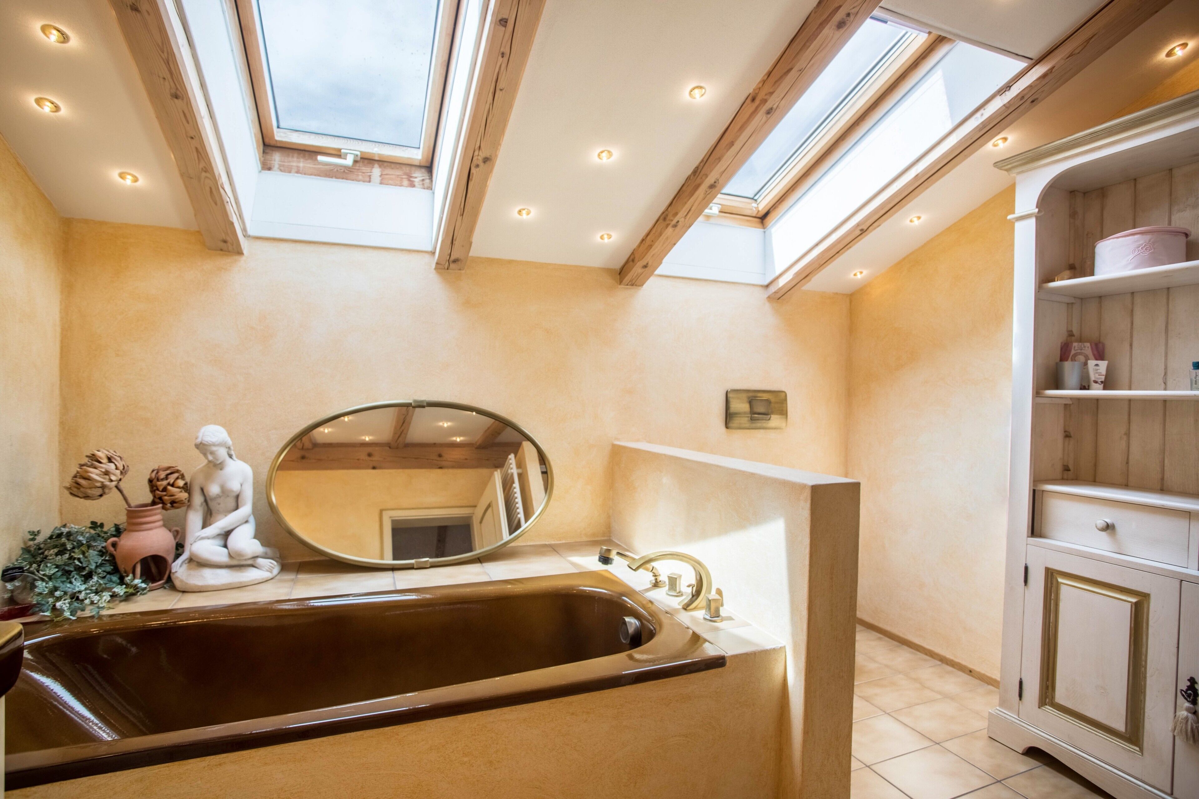 A bathroom with a skylight, a sink, a mirror, and a cabinet.