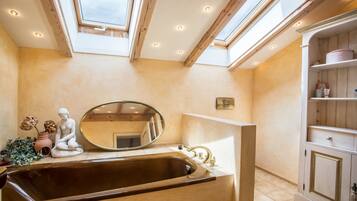 A bathroom with a skylight, a sink, a mirror, and a cabinet.