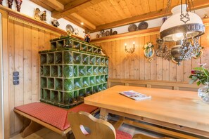 Un intérieur en bois agrémenté d’un mur décoré d’une mosaïque verte, d’un banc en bois, d’une table avec un magazine et d’un lustre.