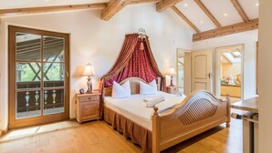 A bedroom with a wooden bed, a canopy, a nightstand, a lamp, and a window with a view. - Spacious Group Holiday Home in Chiemgau – Ideal for Families & Friends (up to 10 guests) (Unterwössen)