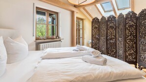 A bedroom with a large bed, a window, and a decorative wooden partition. - Spacious Group Holiday Home in Chiemgau – Ideal for Families & Friends (up to 10 guests) (Unterwössen)