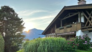 A traditional chalet with a balcony, surrounded by lush greenery and a mountain backdrop. - Spacious Group Holiday Home in Chiemgau – Ideal for Families & Friends (up to 10 guests) (Unterwössen)