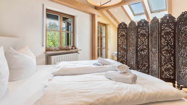 A bedroom with a large bed, a window, and a decorative wooden partition.
