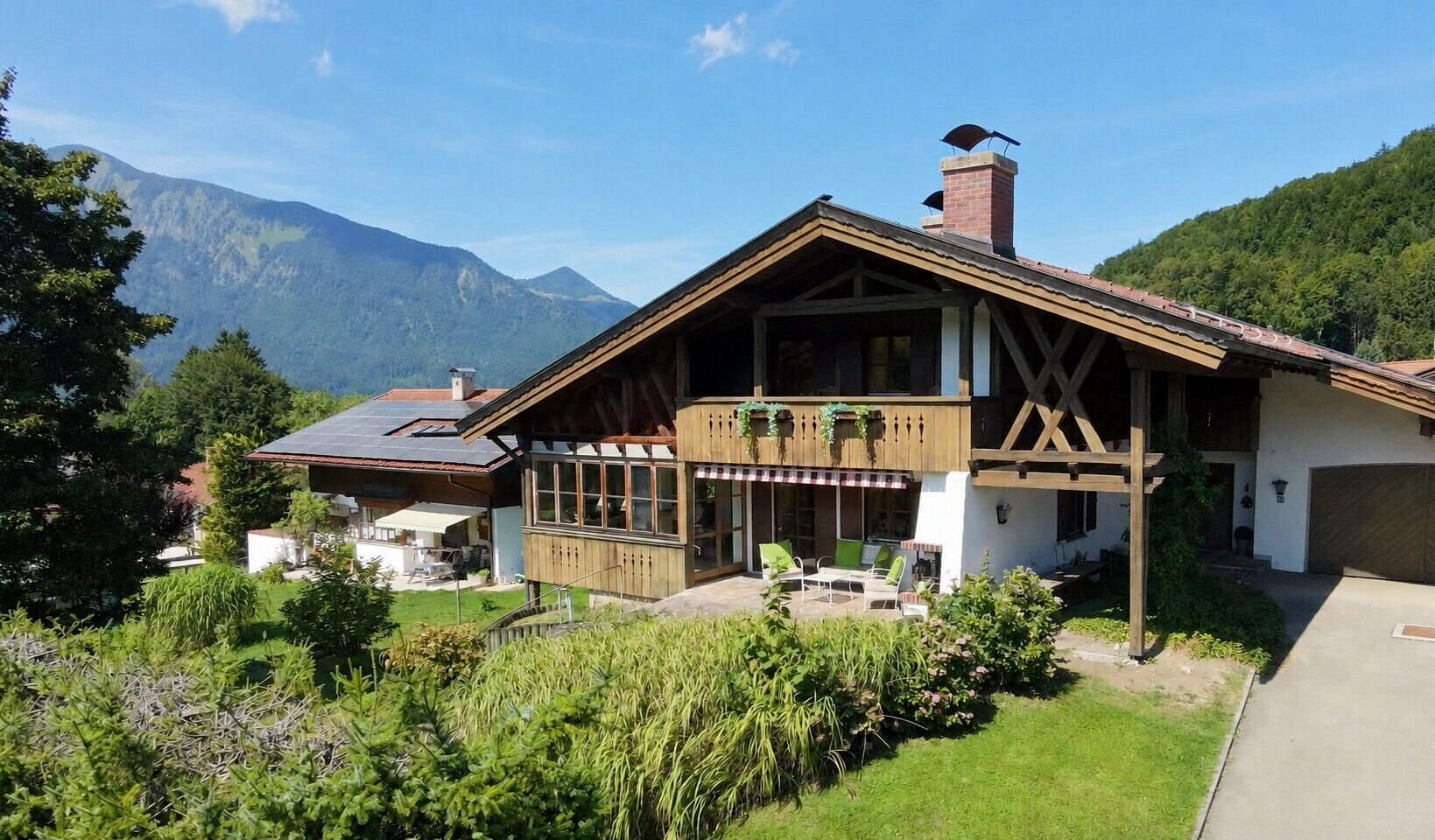 Un chalet con facciata in legno, un balcone con posti a sedere all'aperto e le montagne sullo sfondo.