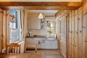 A compact kitchen with wooden cabinetry, a dining table, and a window with a view of the outside.