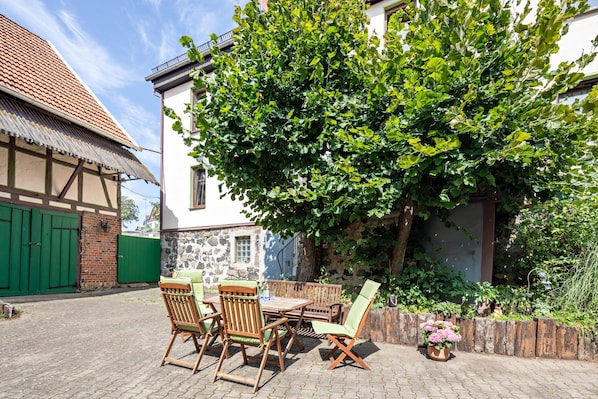 A courtyard with a table and chairs, a green gate, and a tree.