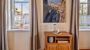 A room with a wooden cabinet, a window with curtains, and a framed picture on the wall.