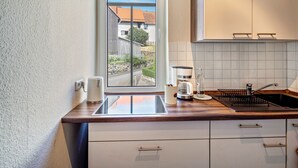 A modern kitchen with a window view, white cabinets, a coffee maker, and a sink.