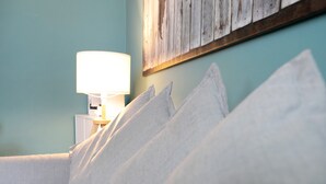 A bed with white pillows and a bedside lamp against teal walls.